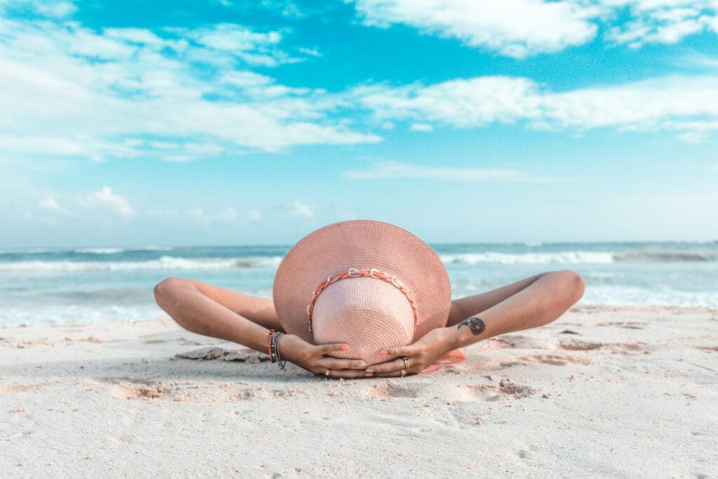 Puerto del Carmen, Lanzarote, showcases a serene beach scene with a woman relaxing on the soft, golden sands, embracing the laid-back and rejuvenating atmosphere, ideal for a tranquil and leisurely retirement by the crystal-clear waters.