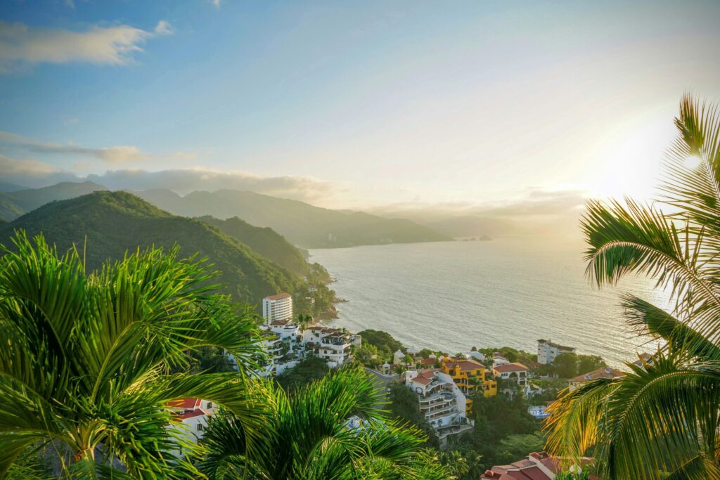 Cobblestone street in Puerto Vallarta gently winding down towards the glistening ocean, with majestic mountains in the distance, offering a picturesque and tranquil setting that encapsulates the charm and beauty of retiring by the sea